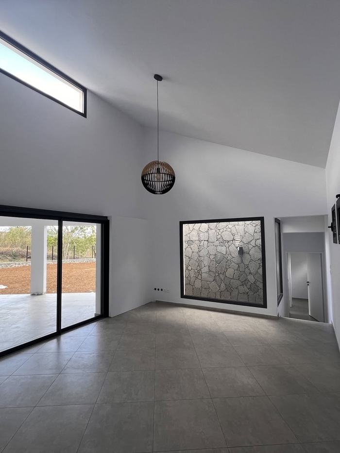 Intérieur avec menuiseries noires, jalousies et mur en pierre encadré