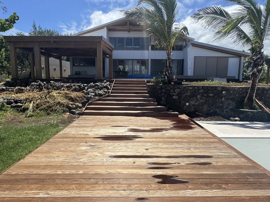 Terrasse et escalier en bois exotique avec mur en pierre de basalte