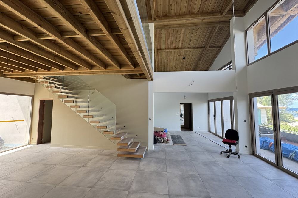 Séjour double hauteur avec charpente bois apparente et escalier suspendu