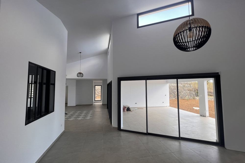Pièce de vie contemporaine, grande hauteur sous plafond et baies noires
